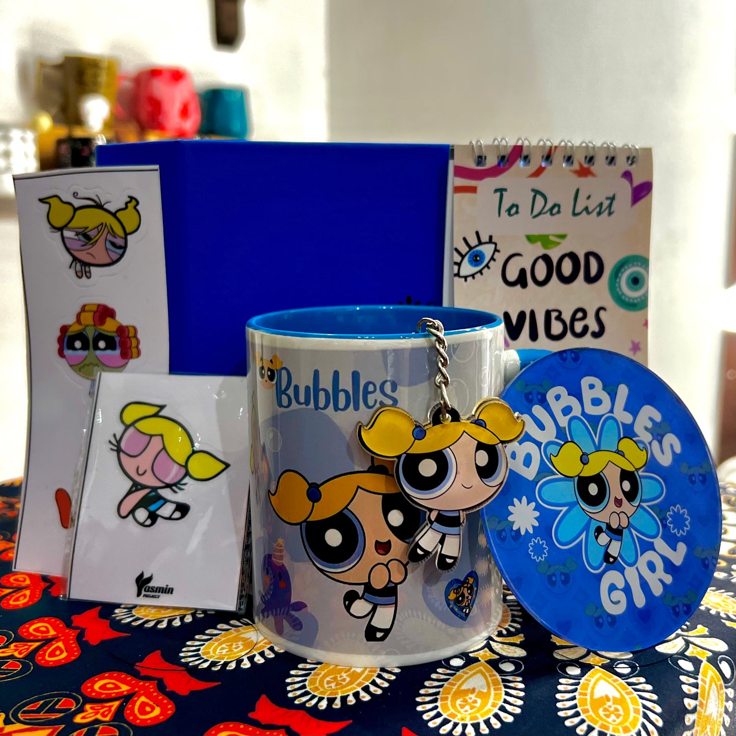 Collection of 'Bubbles' themed merchandise including a mug, keychain, and coasters on a colorful surface.